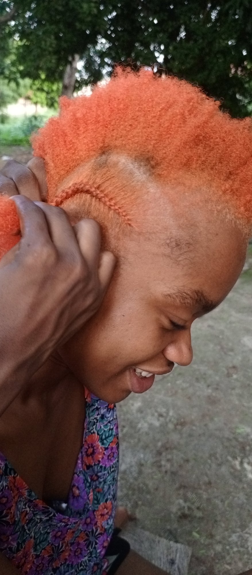 Outdoor hair braiding session captured in casual moment