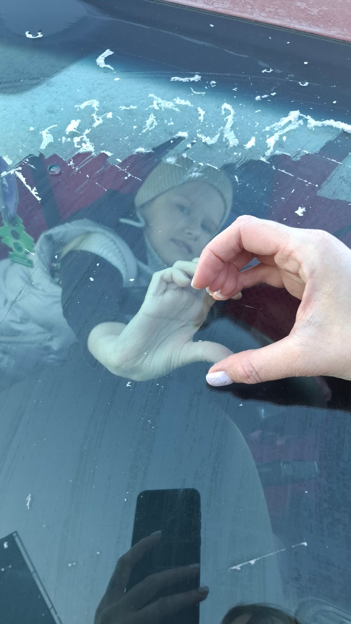 Person clears ice from car windshield in Russia