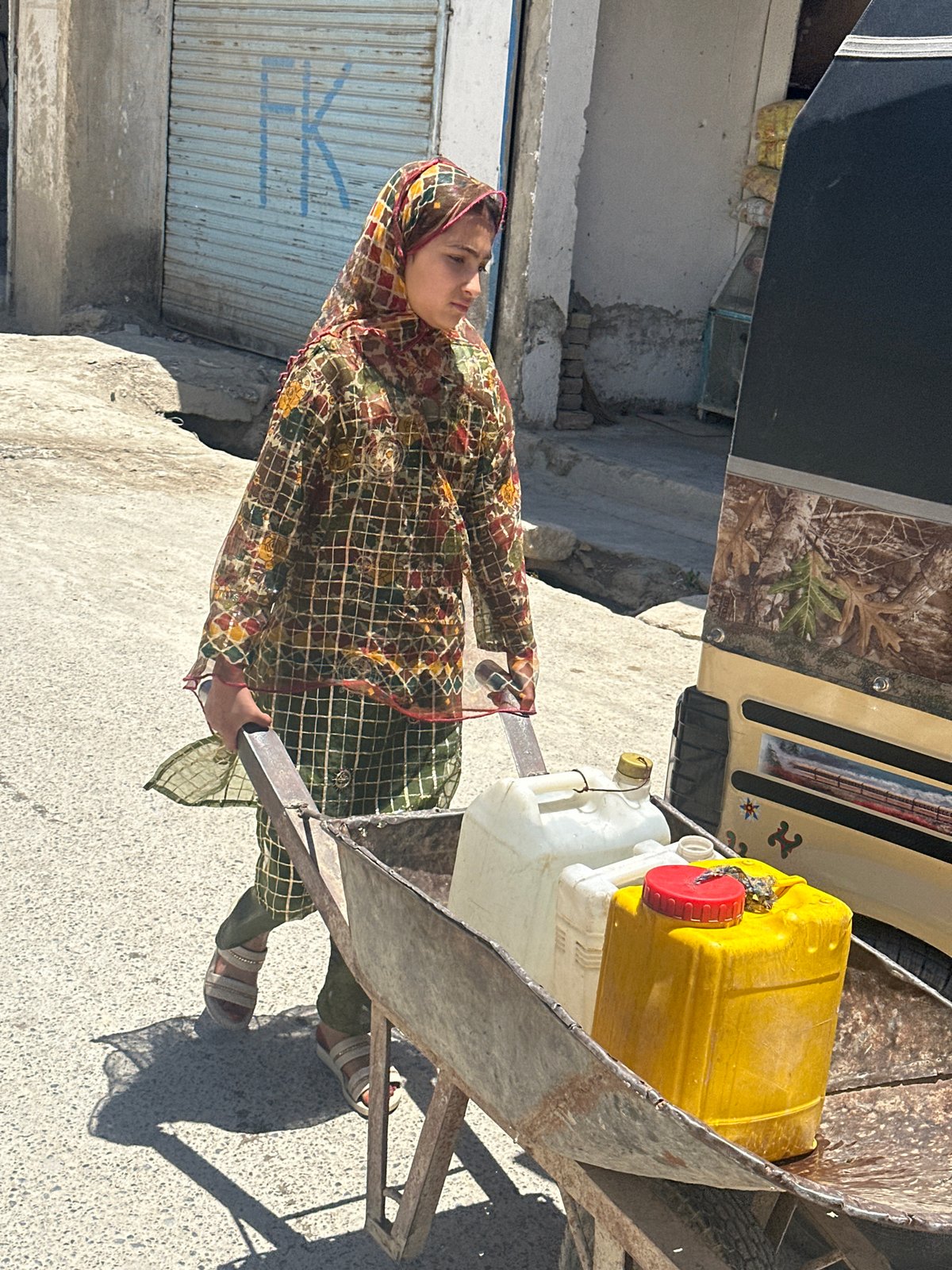 Children pull wheelbarrows through Quetta streets carrying water, refuse