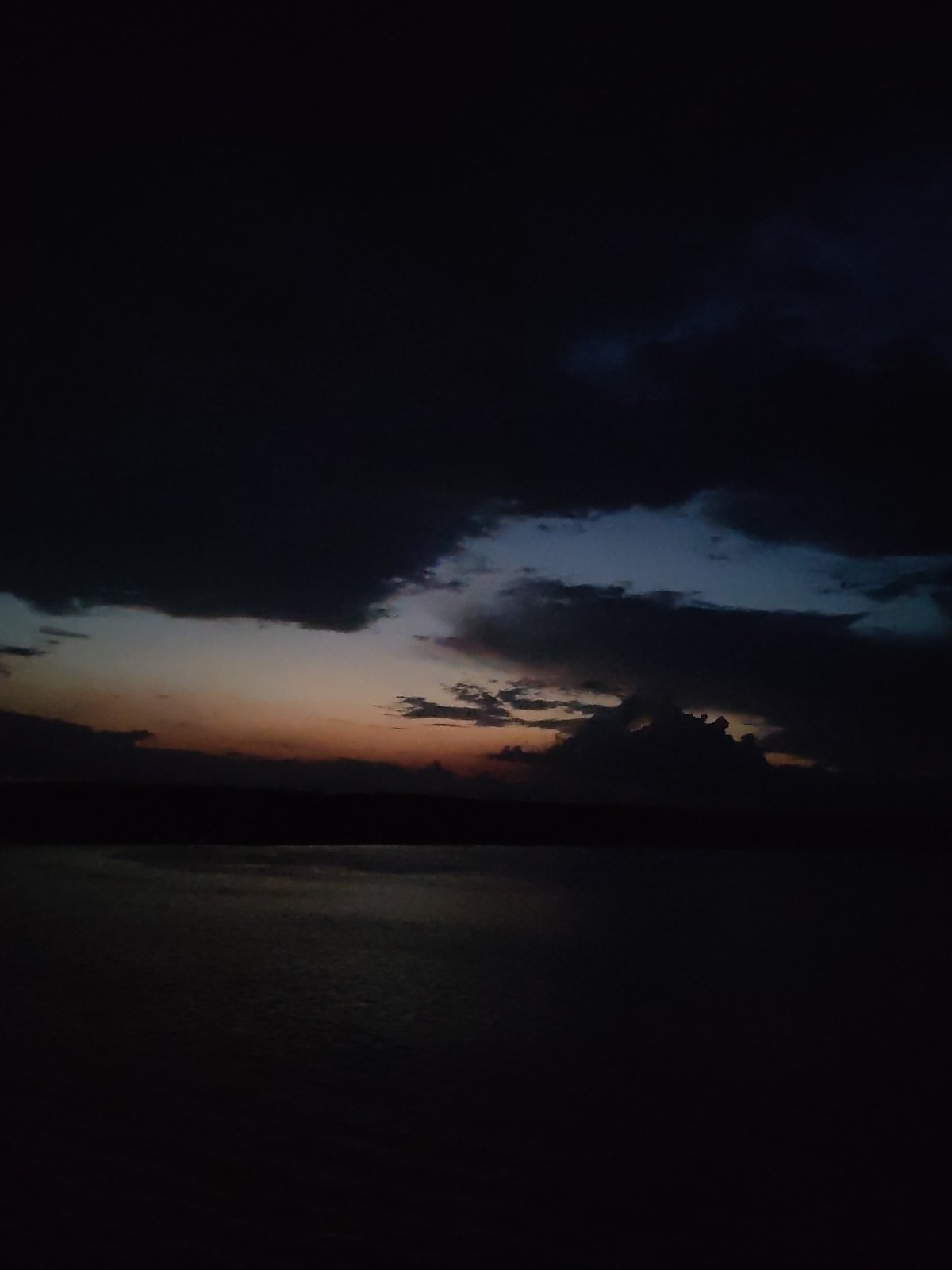 Dark twilight clouds captured over water with sunset glow