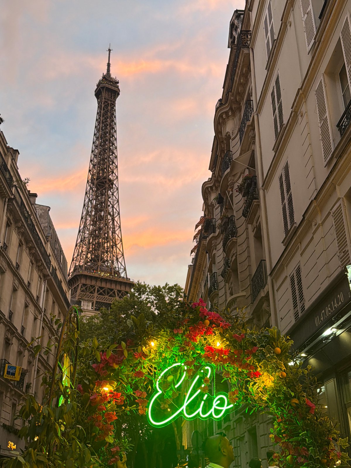Eiffel Tower glows under a pink and orange sunset sky