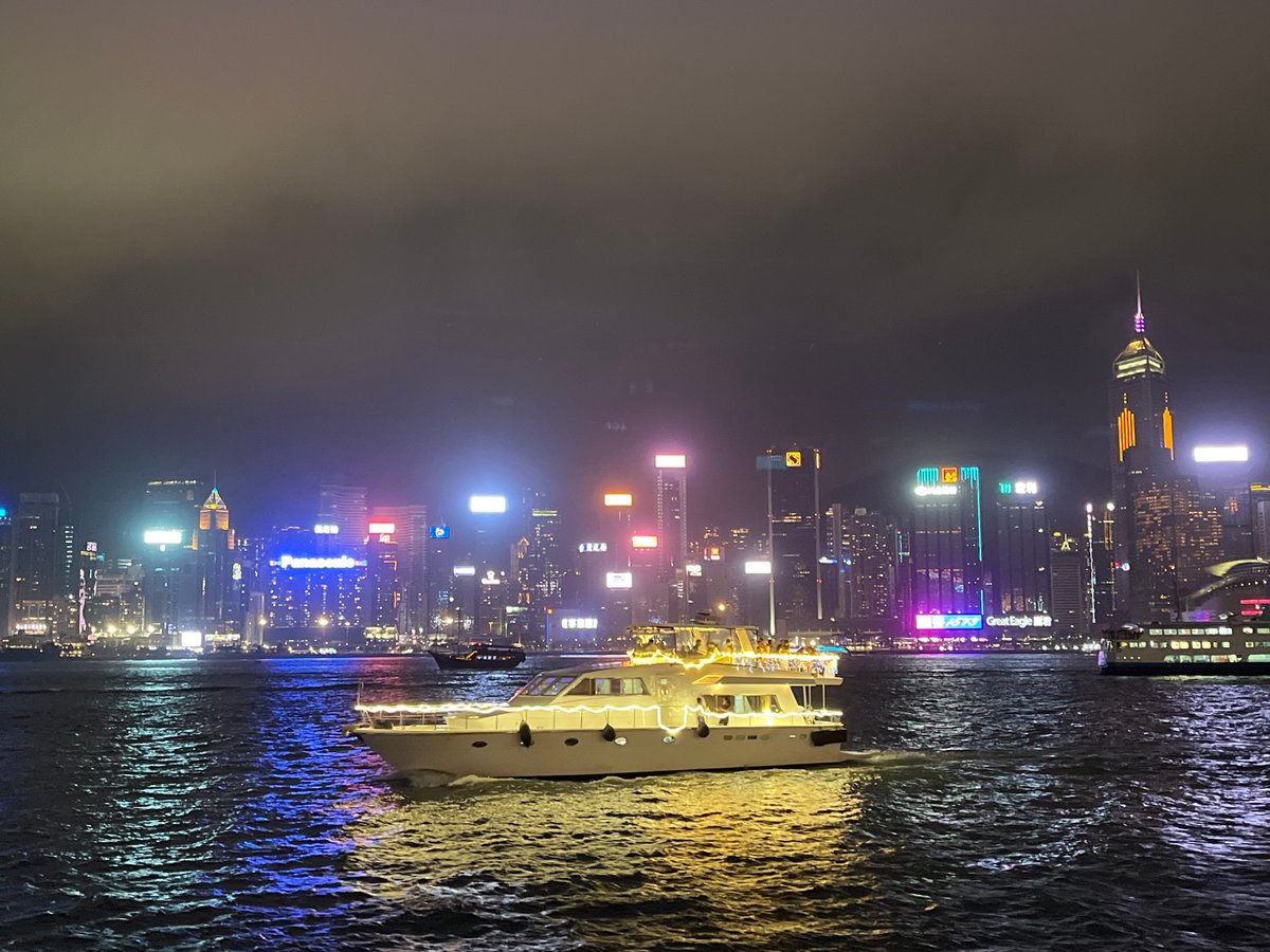 Yacht sails through illuminated Victoria Harbour, Hong Kong