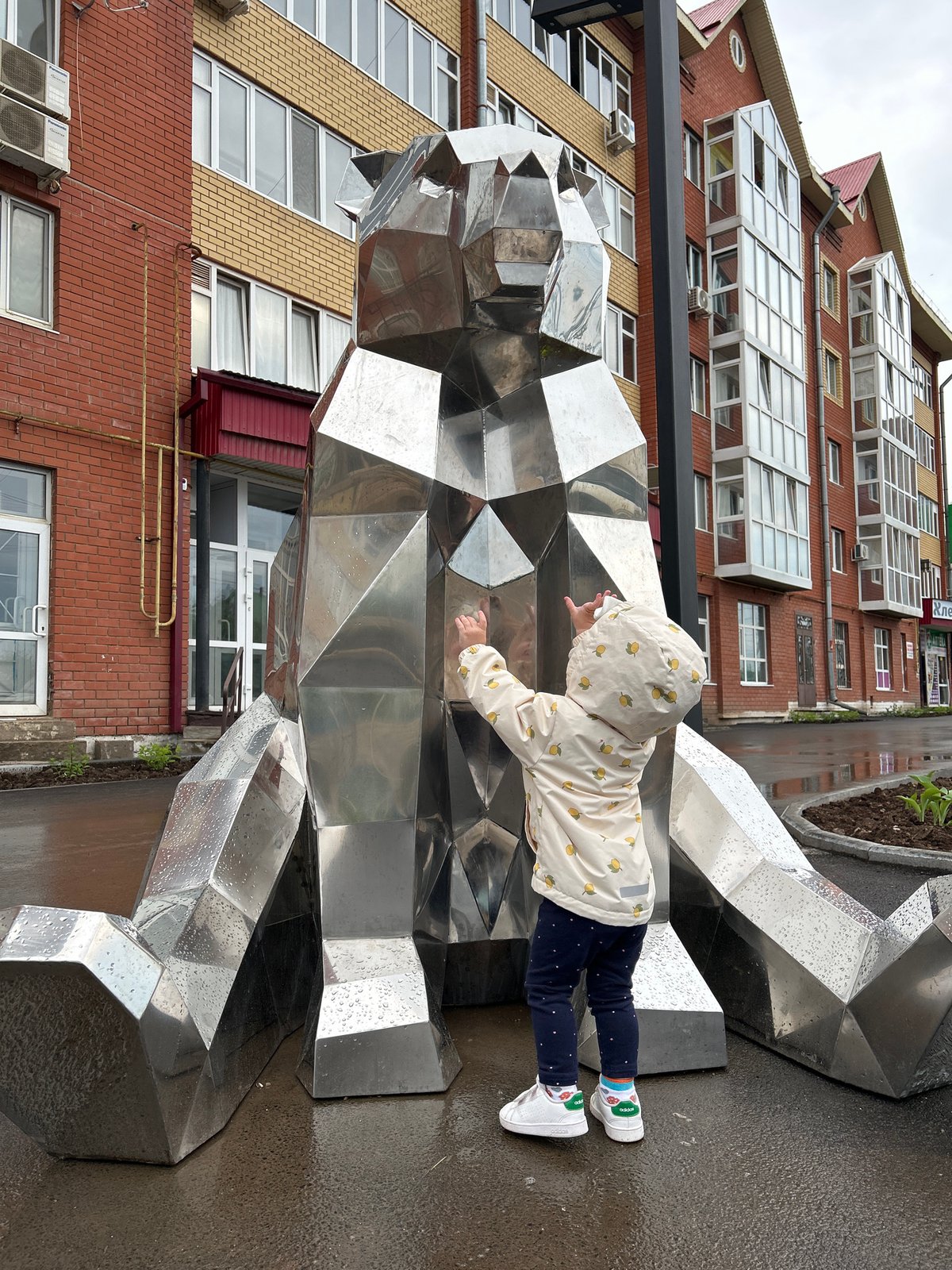 Toddler plays at geometric sculpture in Russian town square