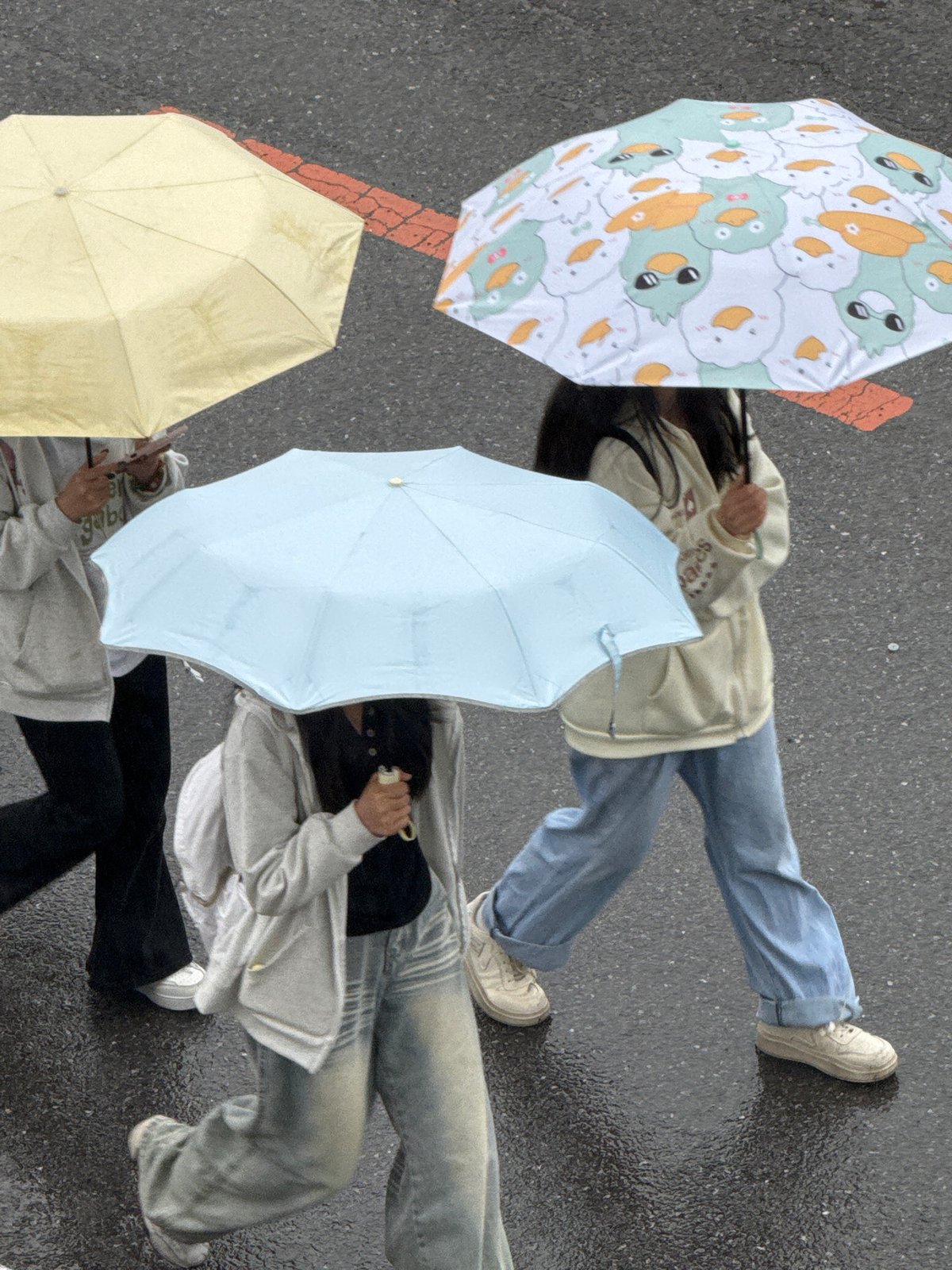 Pedestrians navigate rainy streets with umbrellas in Zhongtun, China