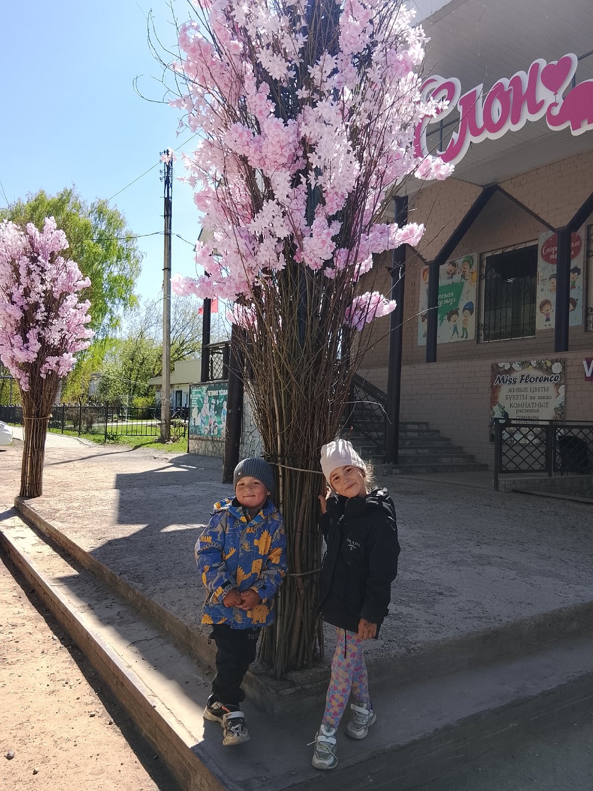 Two children pose by decorative tree in Kuyeda, Russia