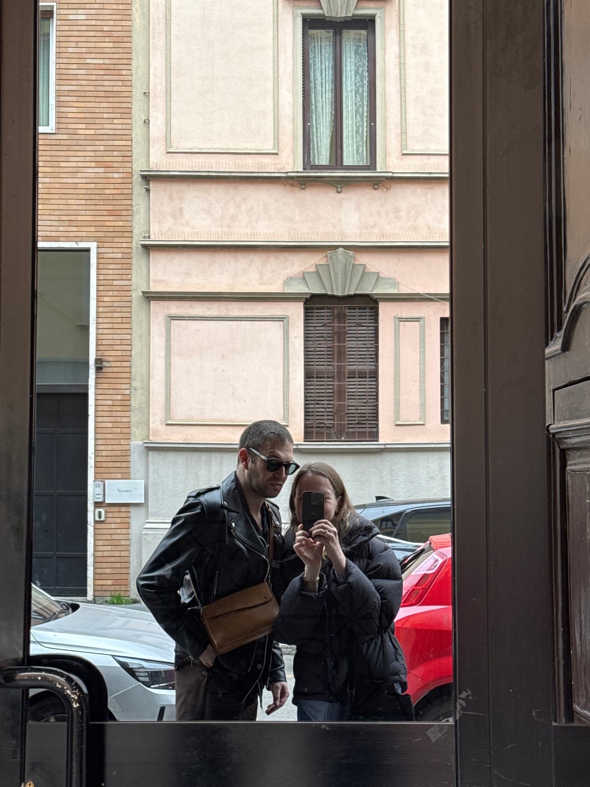 Two people reflected in Milan street glass surface