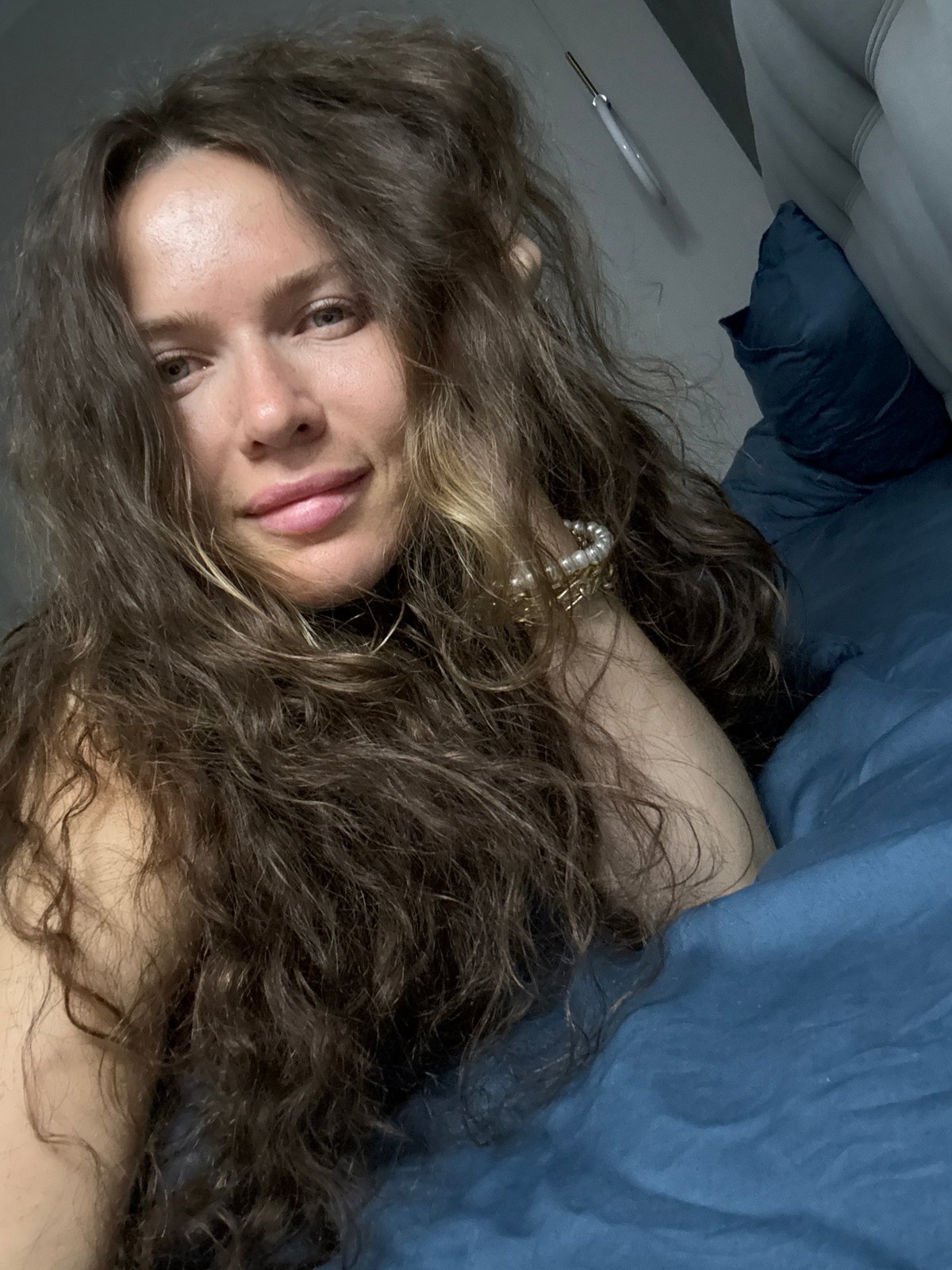Relaxed moment on blue sheets in Khimki, pearl bracelet detail