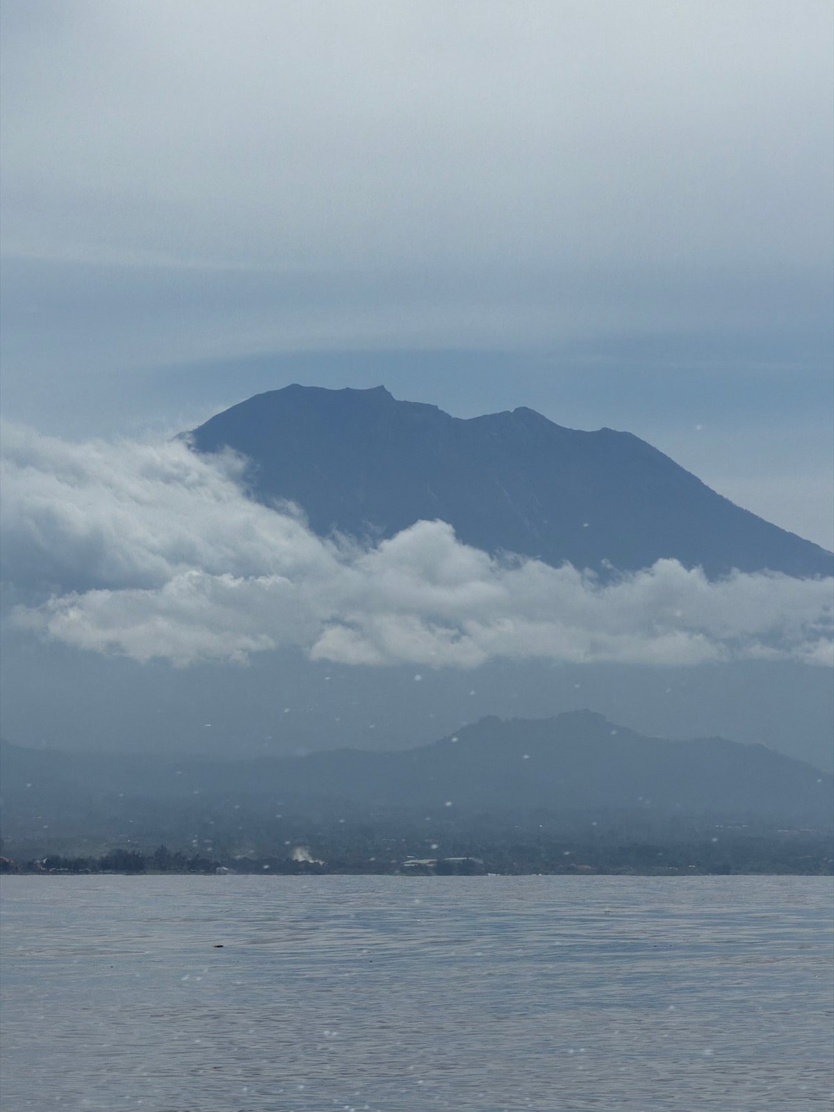 Clouded mountain observed across calm Indonesian waters early morning