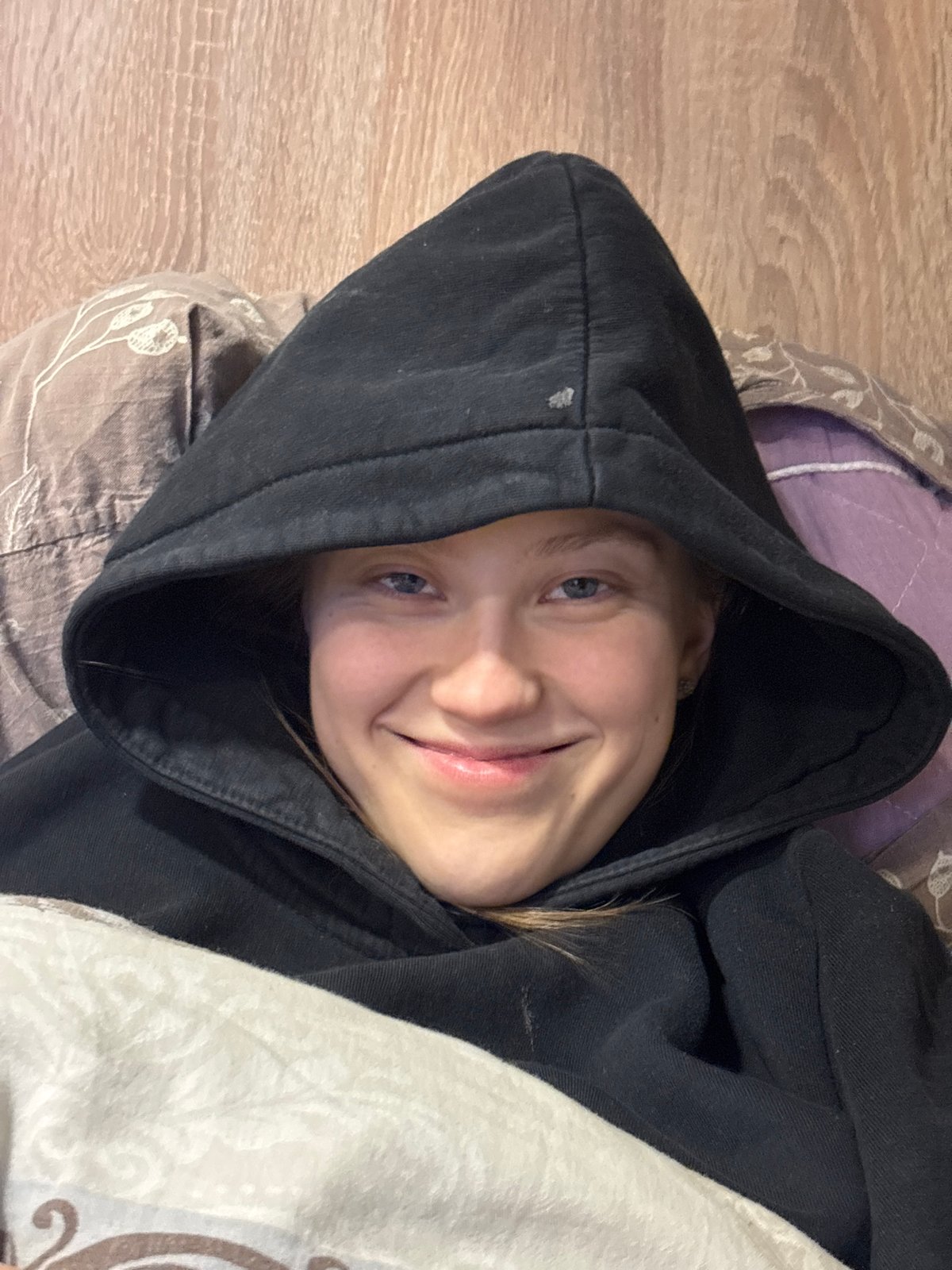 Young person photographed smiling on bed in Perm