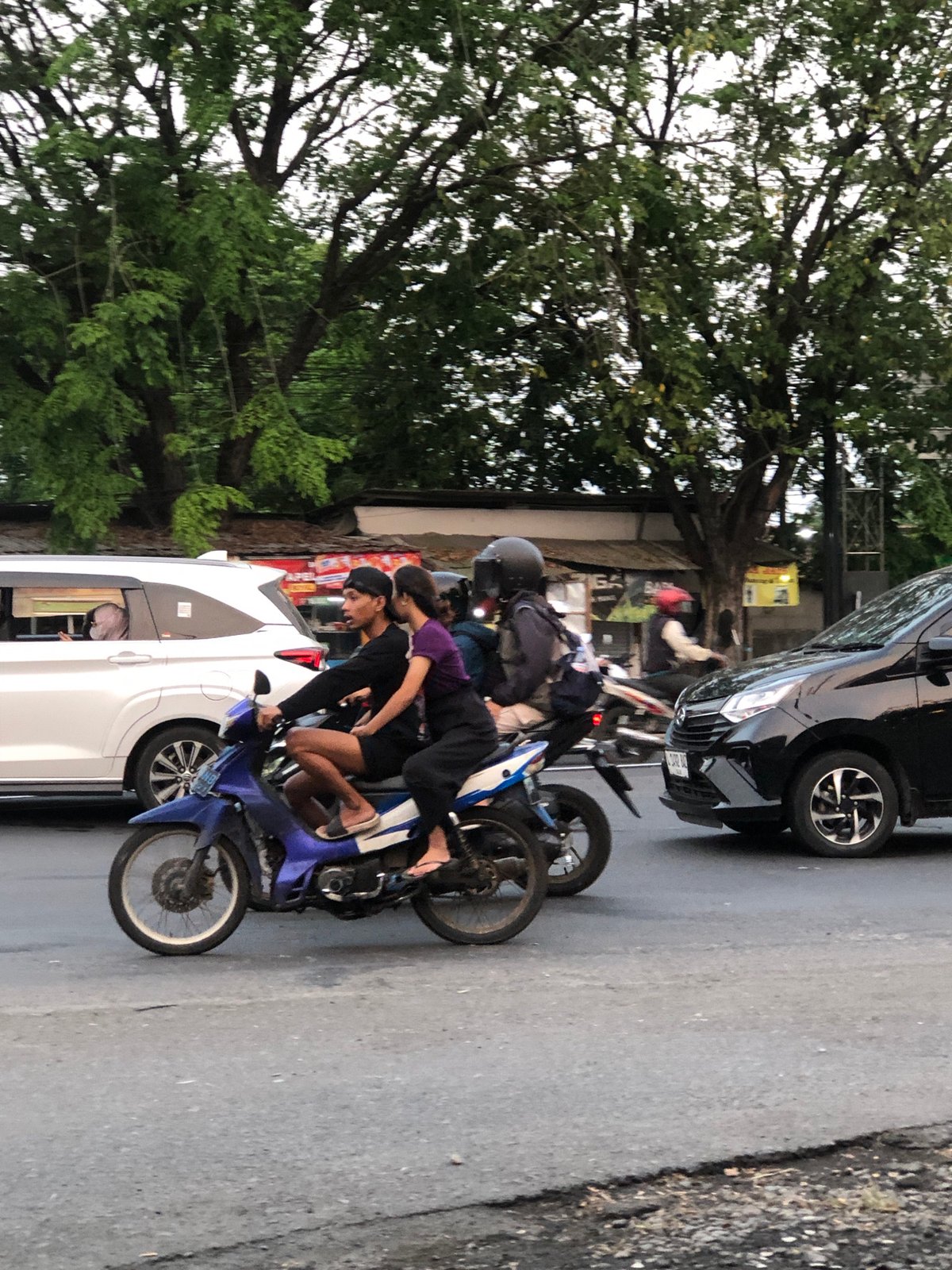 Mixed traffic moves through a busy Kludan street on a cloudy morning