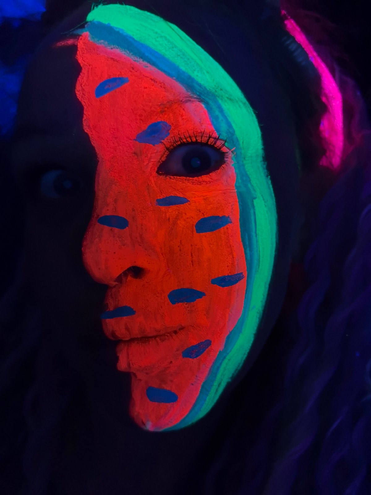UV-lit watermelon face paint art captured in Noviy, Russia