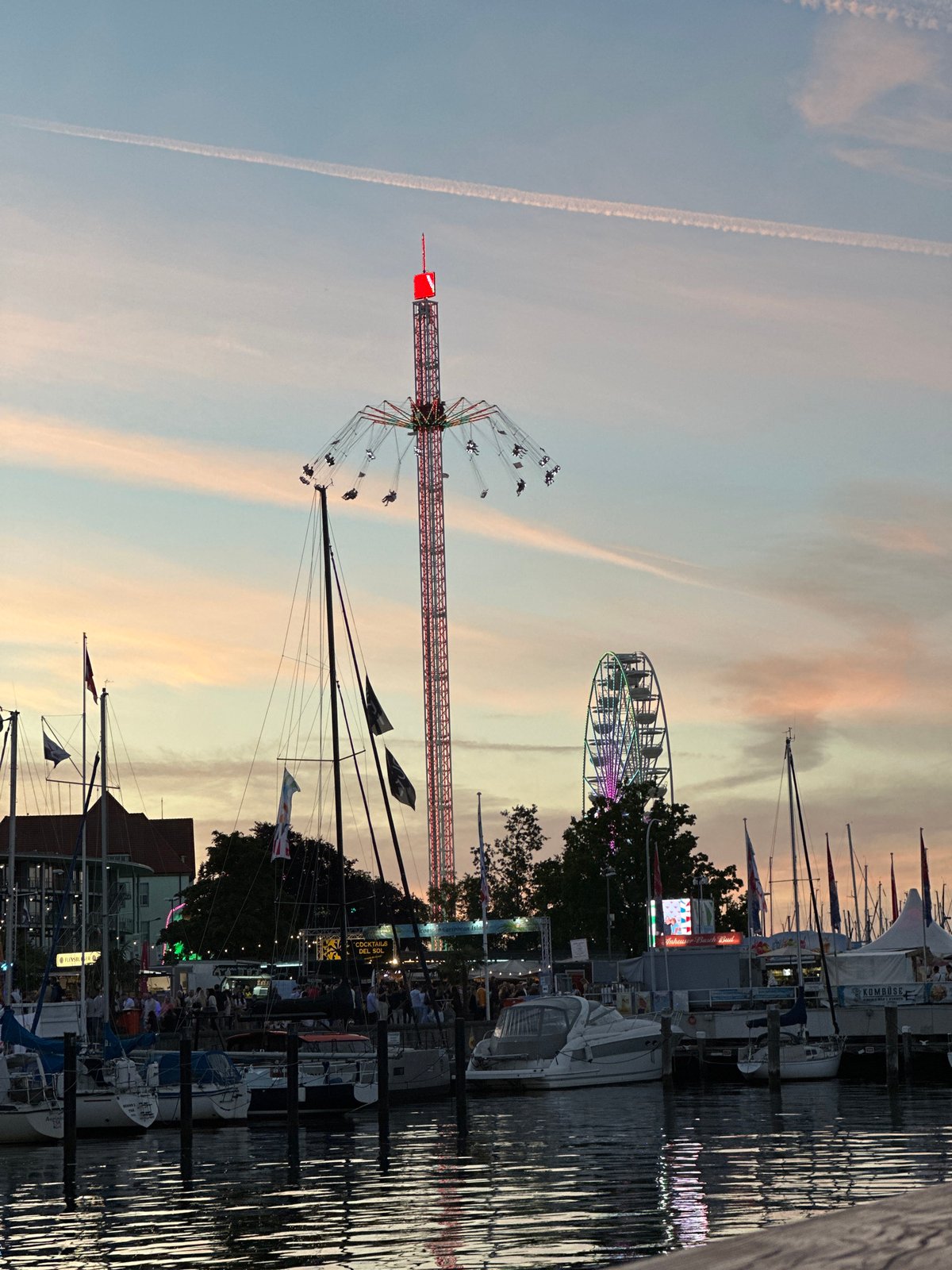Evening festival crowds and lit rides along Kiel's harbor