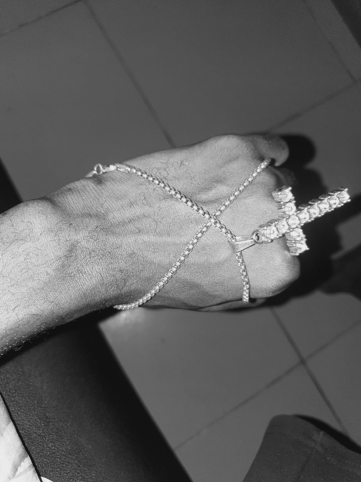 Person displays cross jewelry in artistic photo session in Lokoja