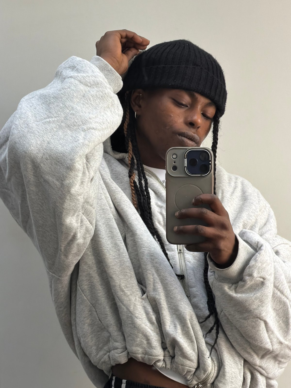 Person takes selfie in grey hoodie against wall in London