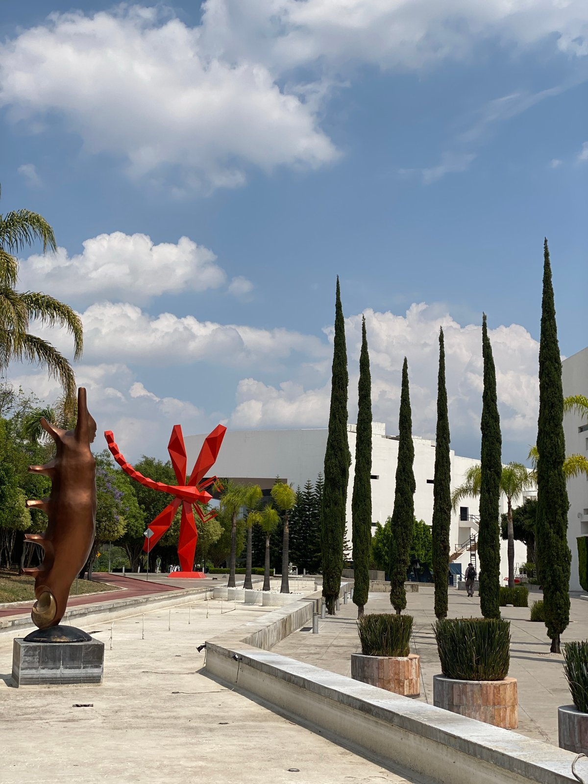 Metallic bovine sculpture observed alongside red geometric structure