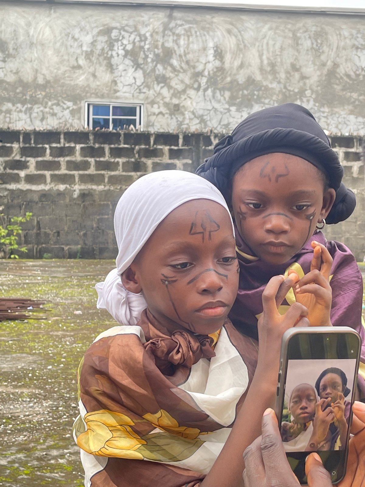 Children in traditional dress with face paint documented in Ado