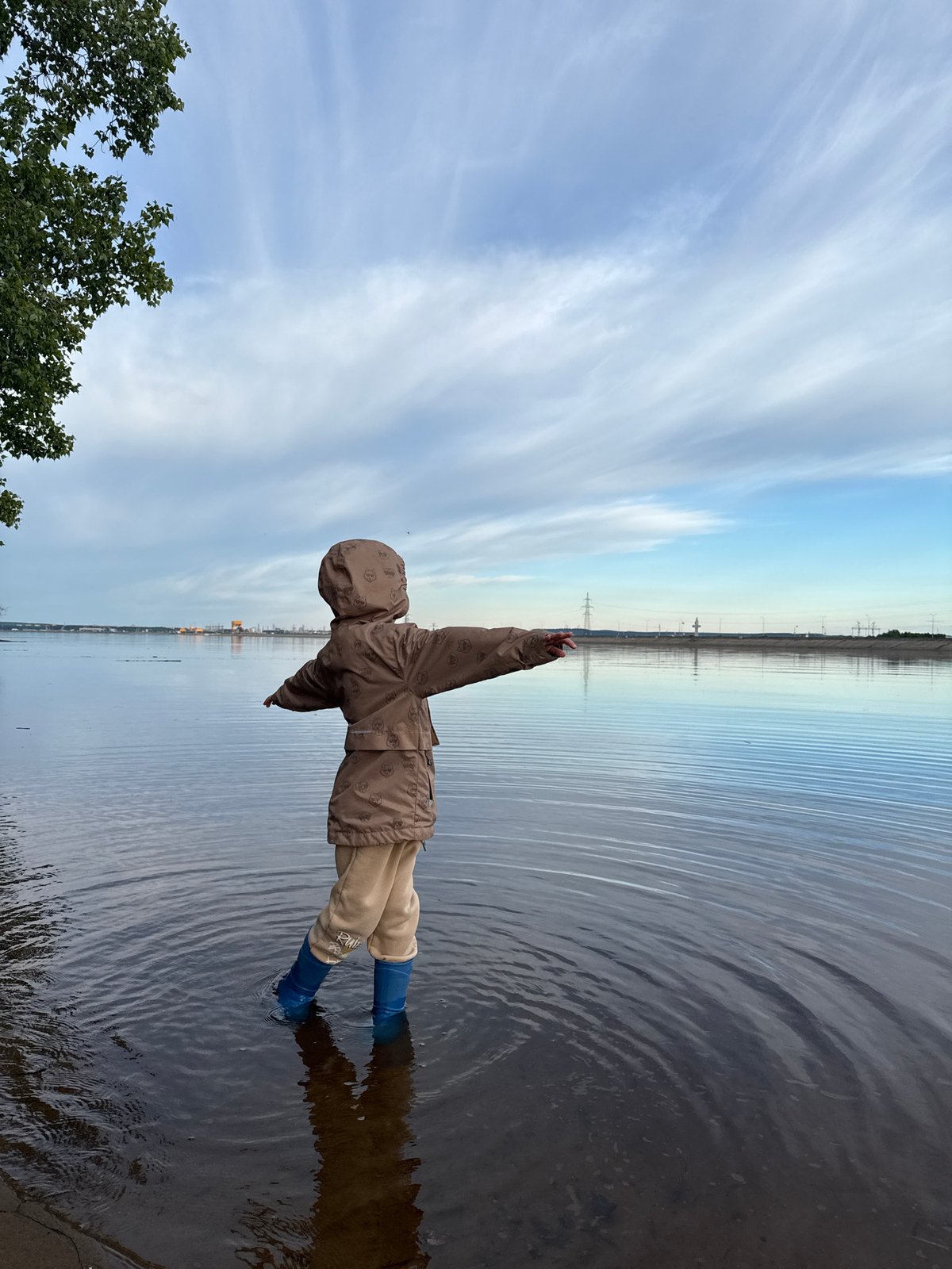 Child plays in shallow water near Noviy, Russia riverbank