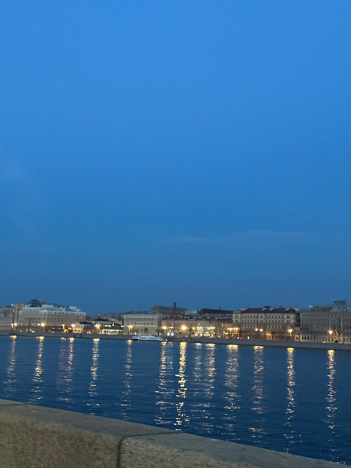 Dusk waterfront cityscape observed with reflective river lights