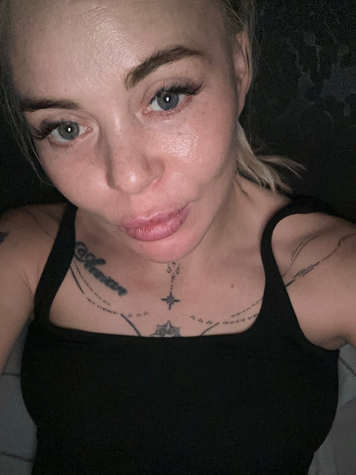 Woman documents extended selfie session in dark indoor setting