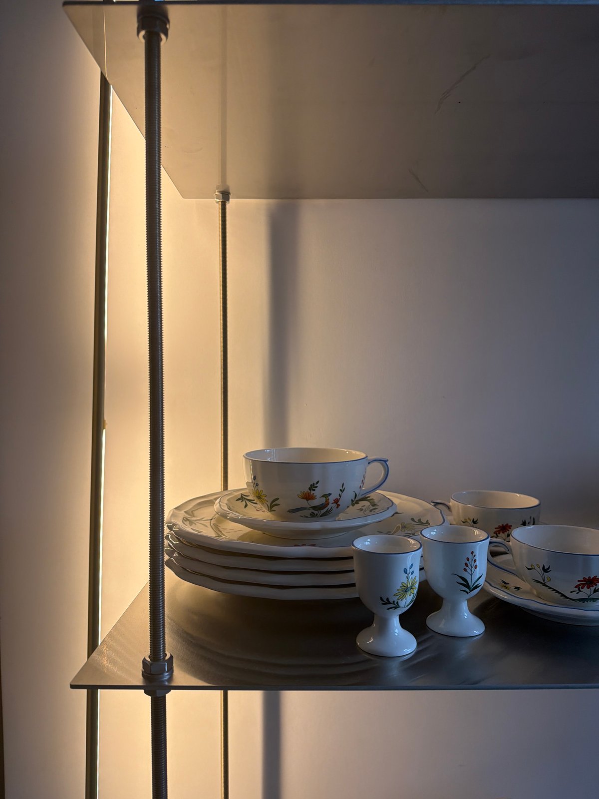 White ceramic dinnerware collection displayed on modern shelving unit