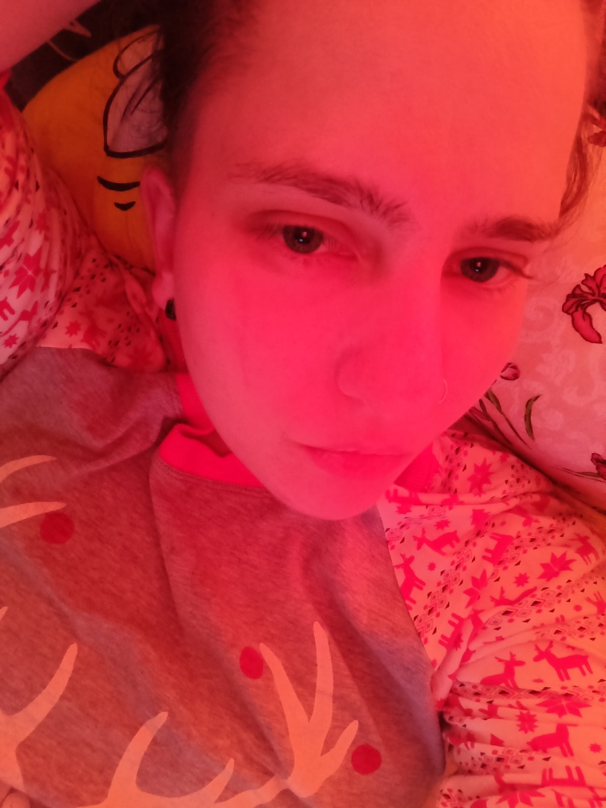 Person rests in bed under red-pink lighting