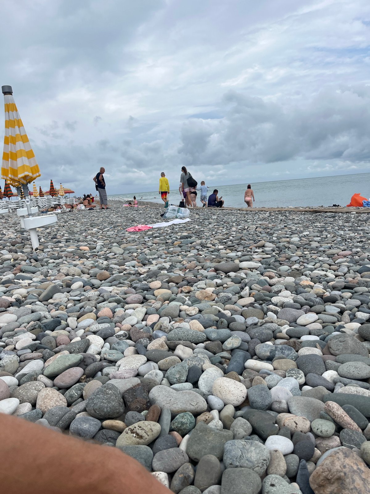 Busy morning on Batumi's pebble beach under cloudy skies