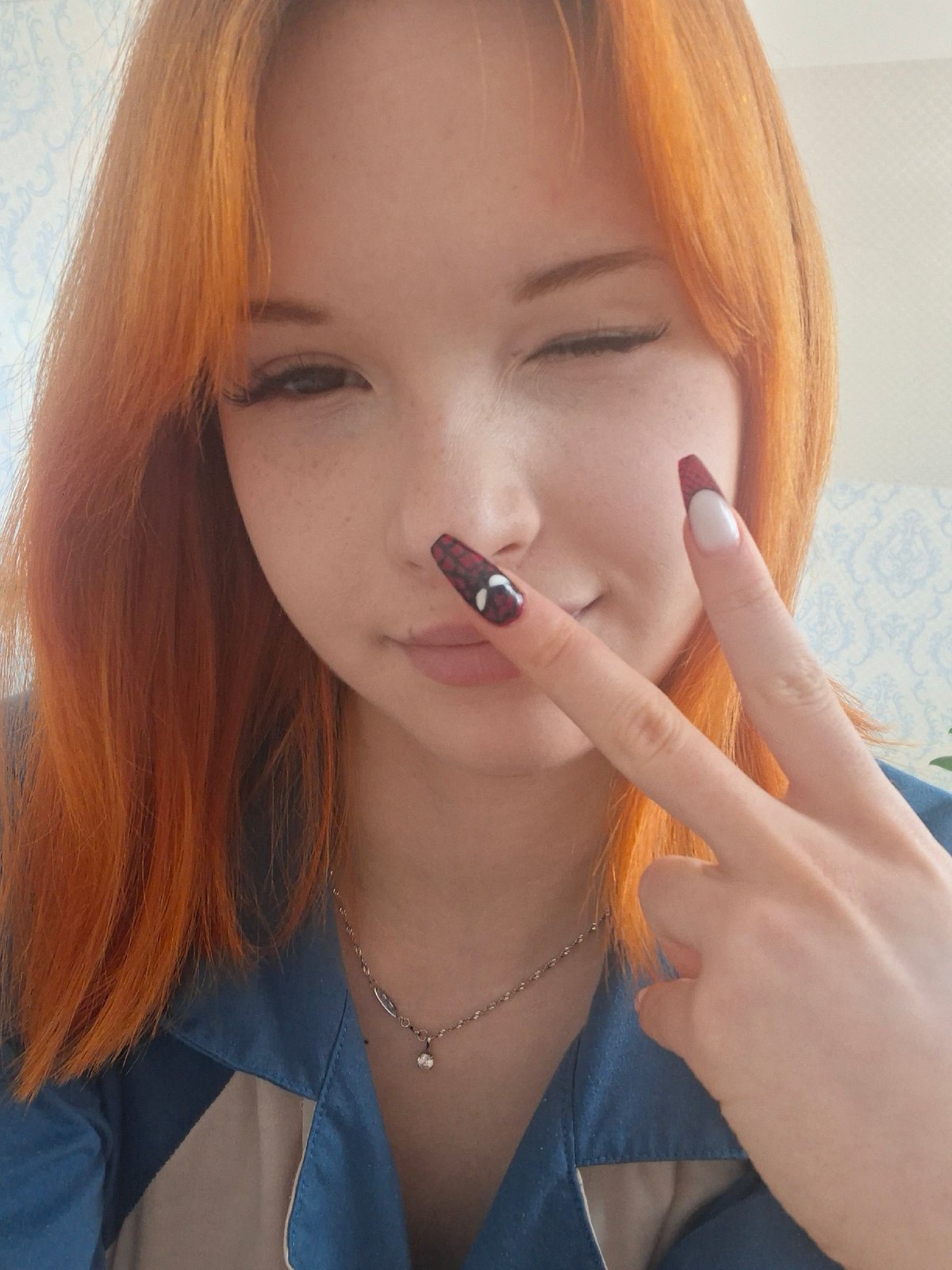 Orange-haired woman poses playfully indoors in Chaikovsky, Russia