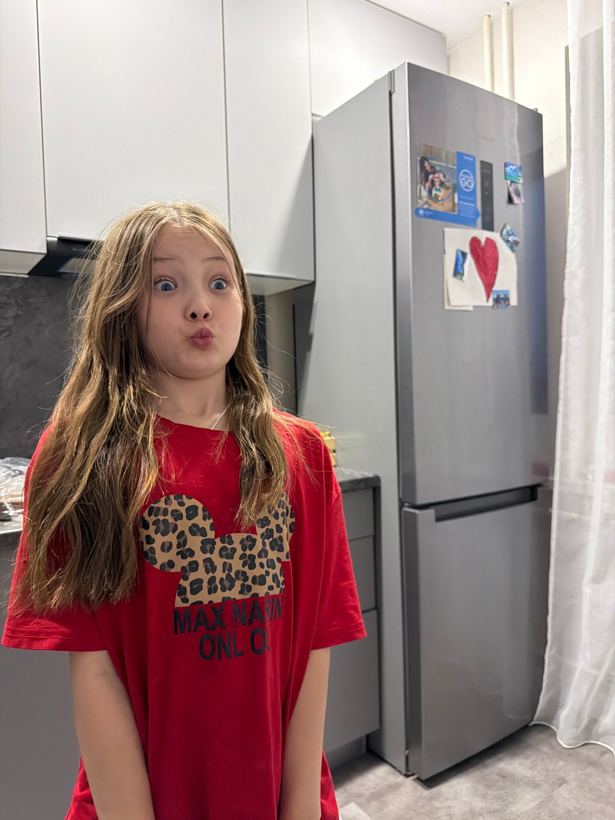 Girl poses in kitchen, makes peace sign in Chaikovsky
