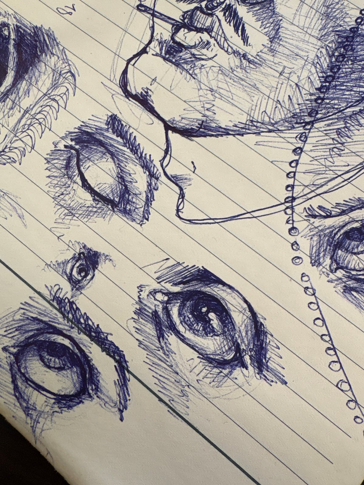 Artist sketches multiple eyes in blue ink, Sofia notebook