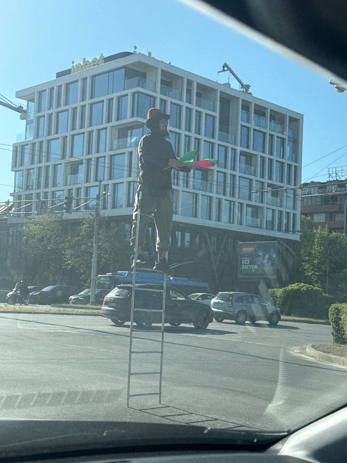 Street performer juggles clubs on Sofia sidewalk and ladder