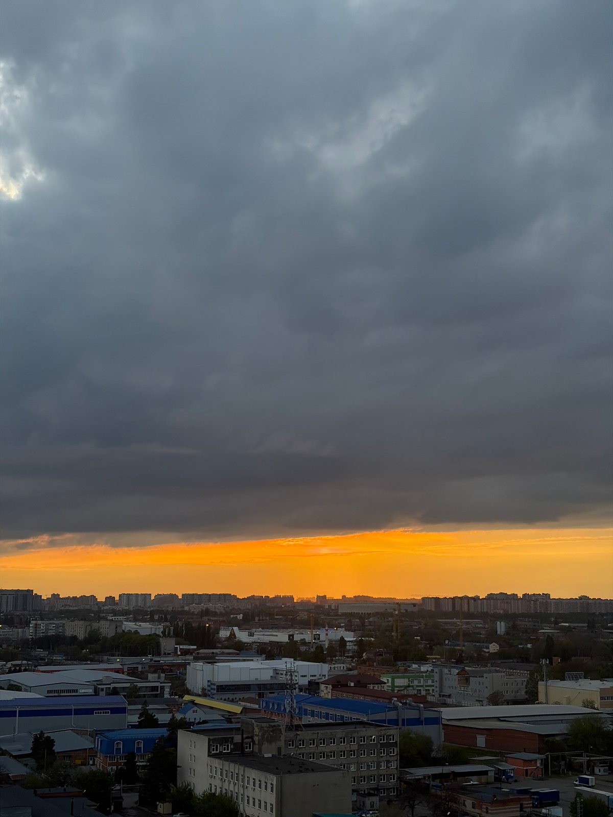 Dramatic storm clouds contrast golden light over Krasnodar cityscape