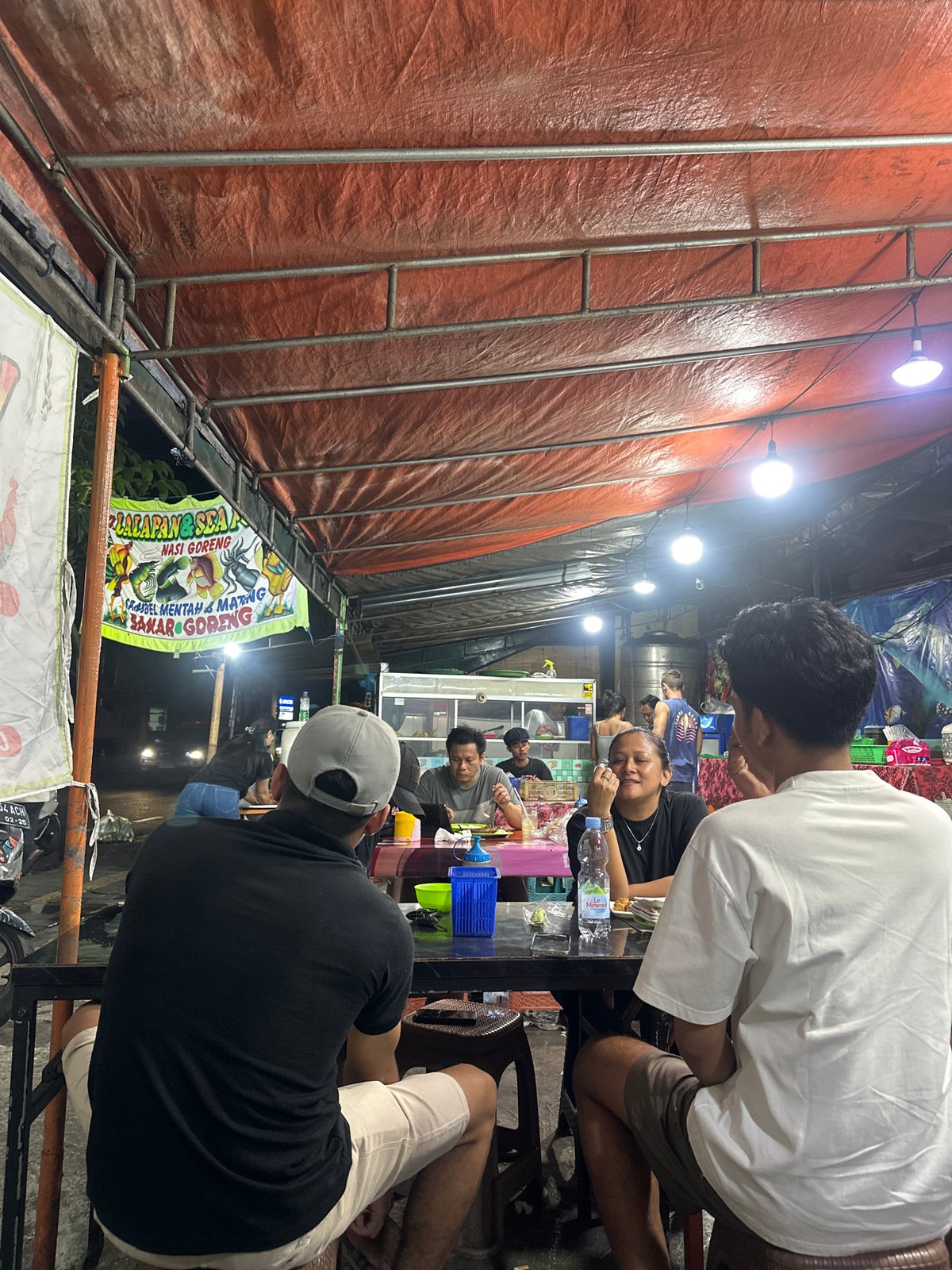 Evening food stall activity and stray cat scavenging in Denpasar