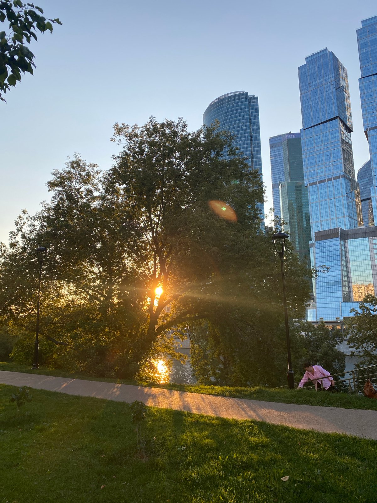Sunset in a Moscow waterfront park beside glass skyscrapers