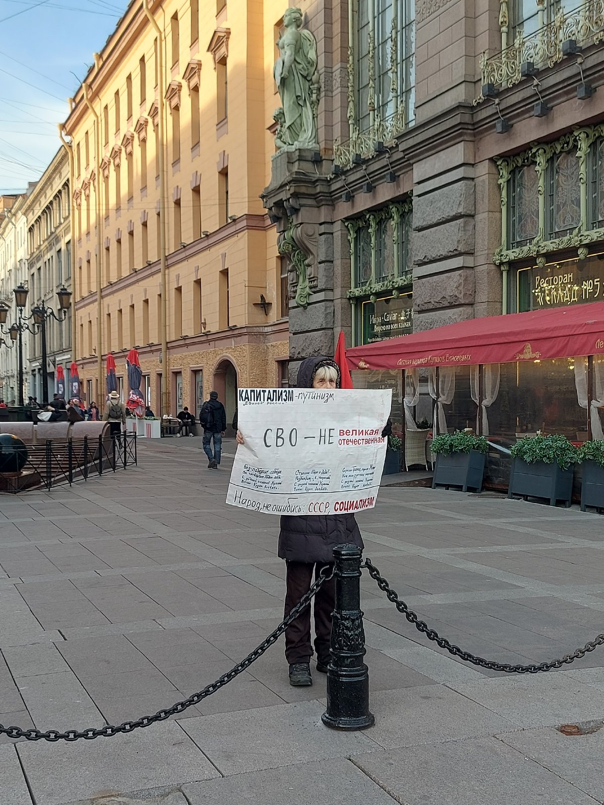 Anti-capitalism protester demonstrates in Saint Petersburg amid motorcycle traffic