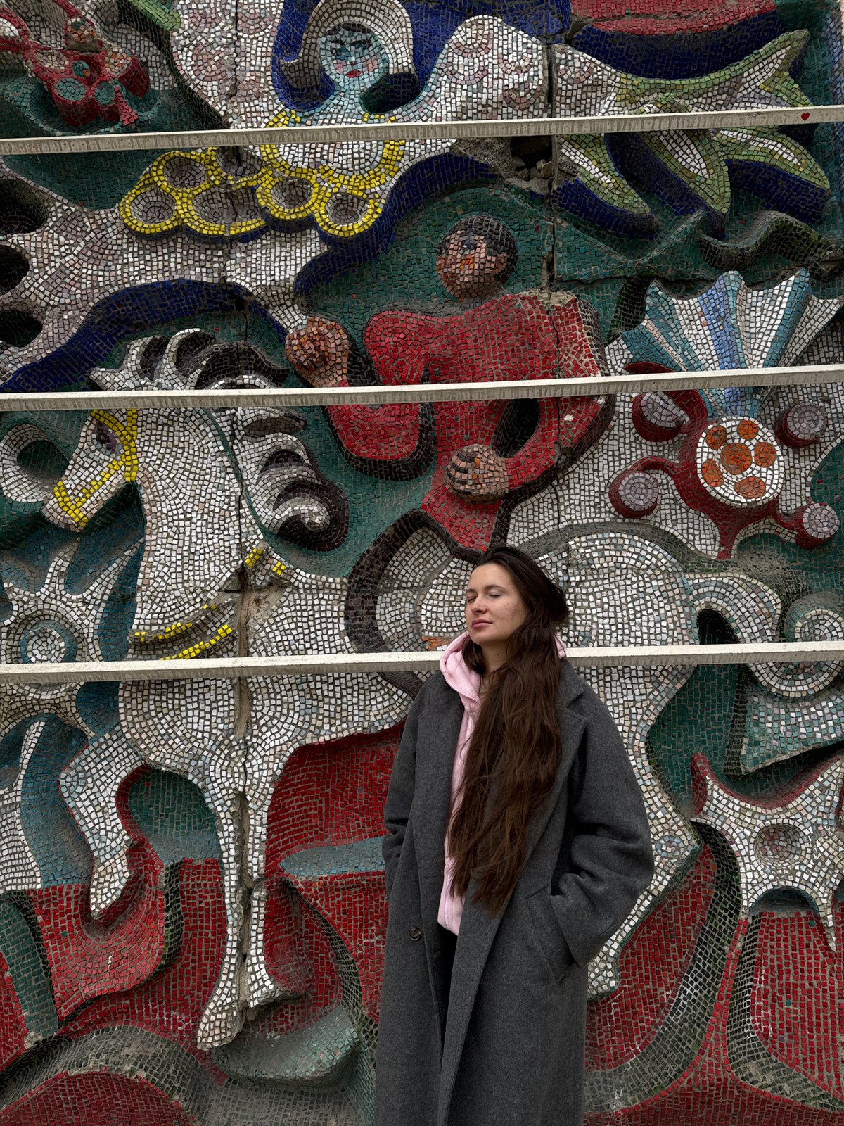 Woman rests at mosaic wall during Easter weekend morning