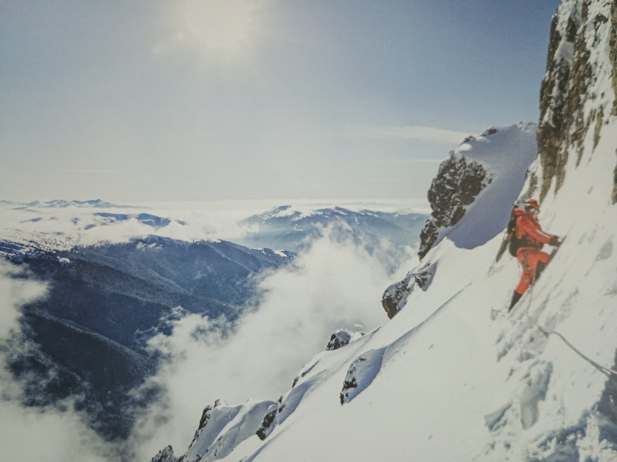 Climber in red gear ascends snowy mountain peak