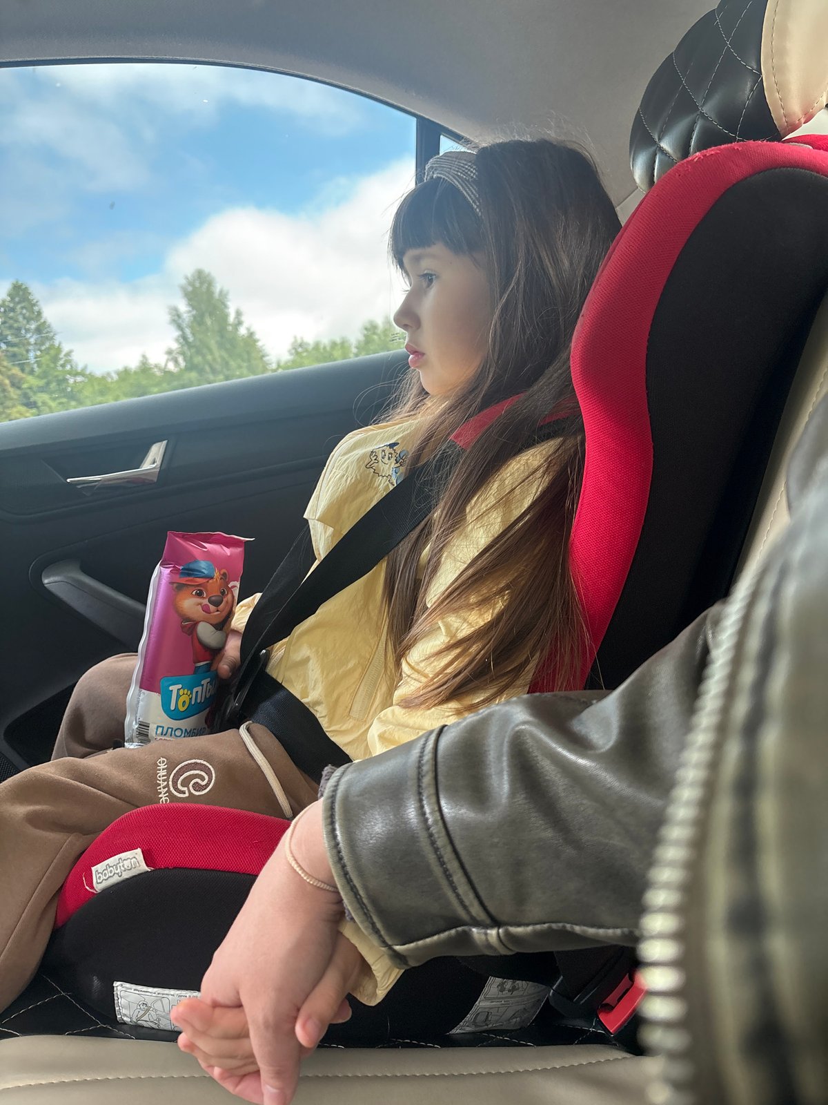 Child with cartoon package observed in car seat, Chaikovsky