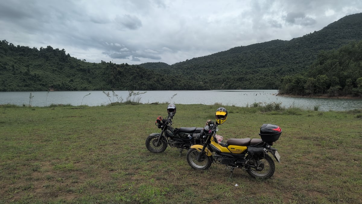 Two adventure bikes parked lakeside on a cloudy day in Vietnam