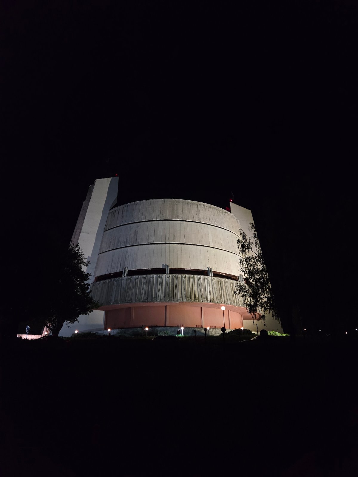 Nighttime architectural structure photographed near parked vehicle