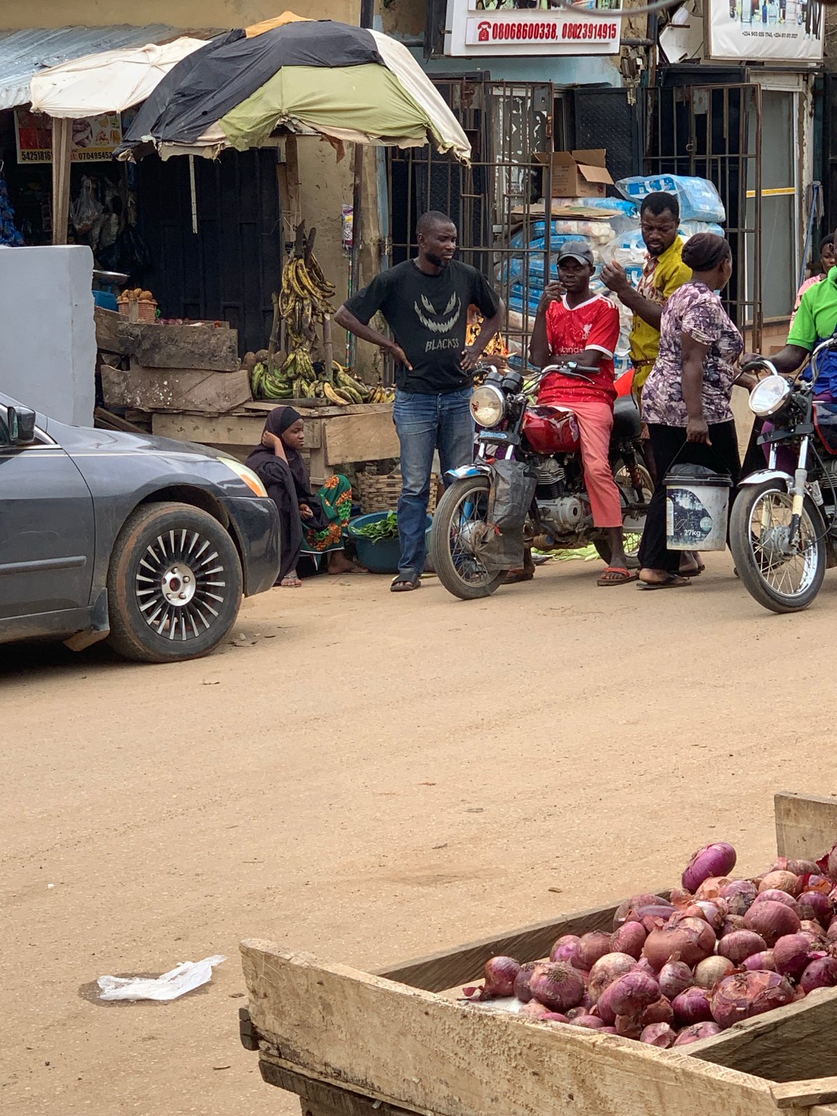Abuja street market buzzing with vendors, pedestrians, and motos