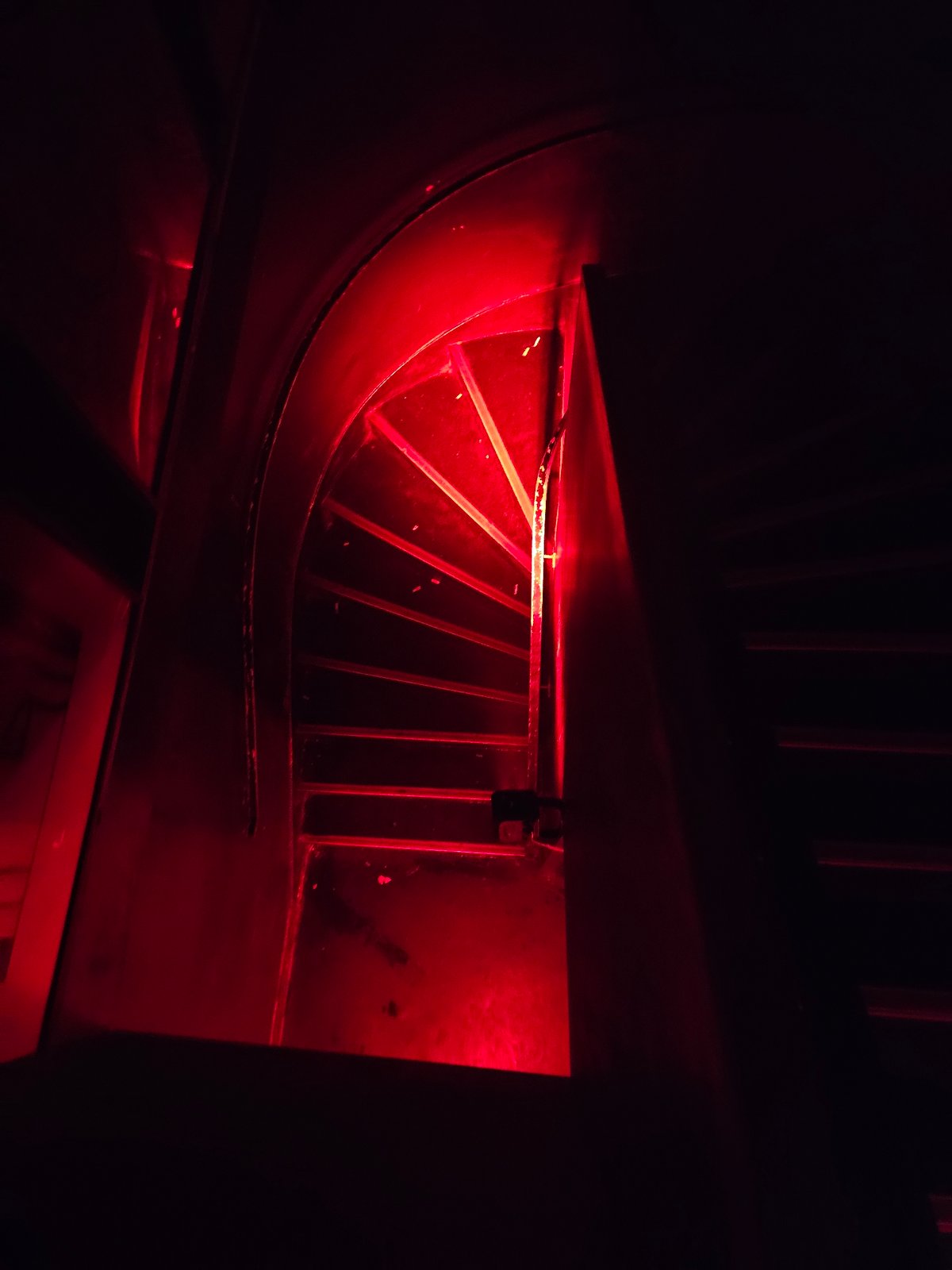 Red-lit machinery grate observed at unknown location