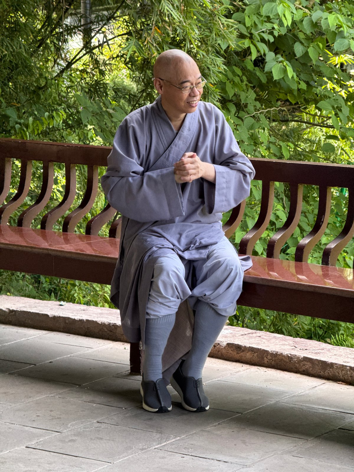 Person in gray robe rests on bench in Jiulongpo District