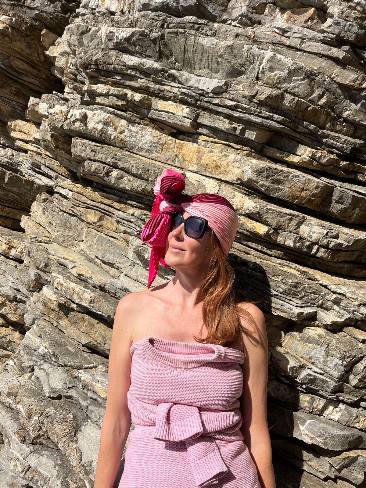 Woman in pink rests on rocks near Budva