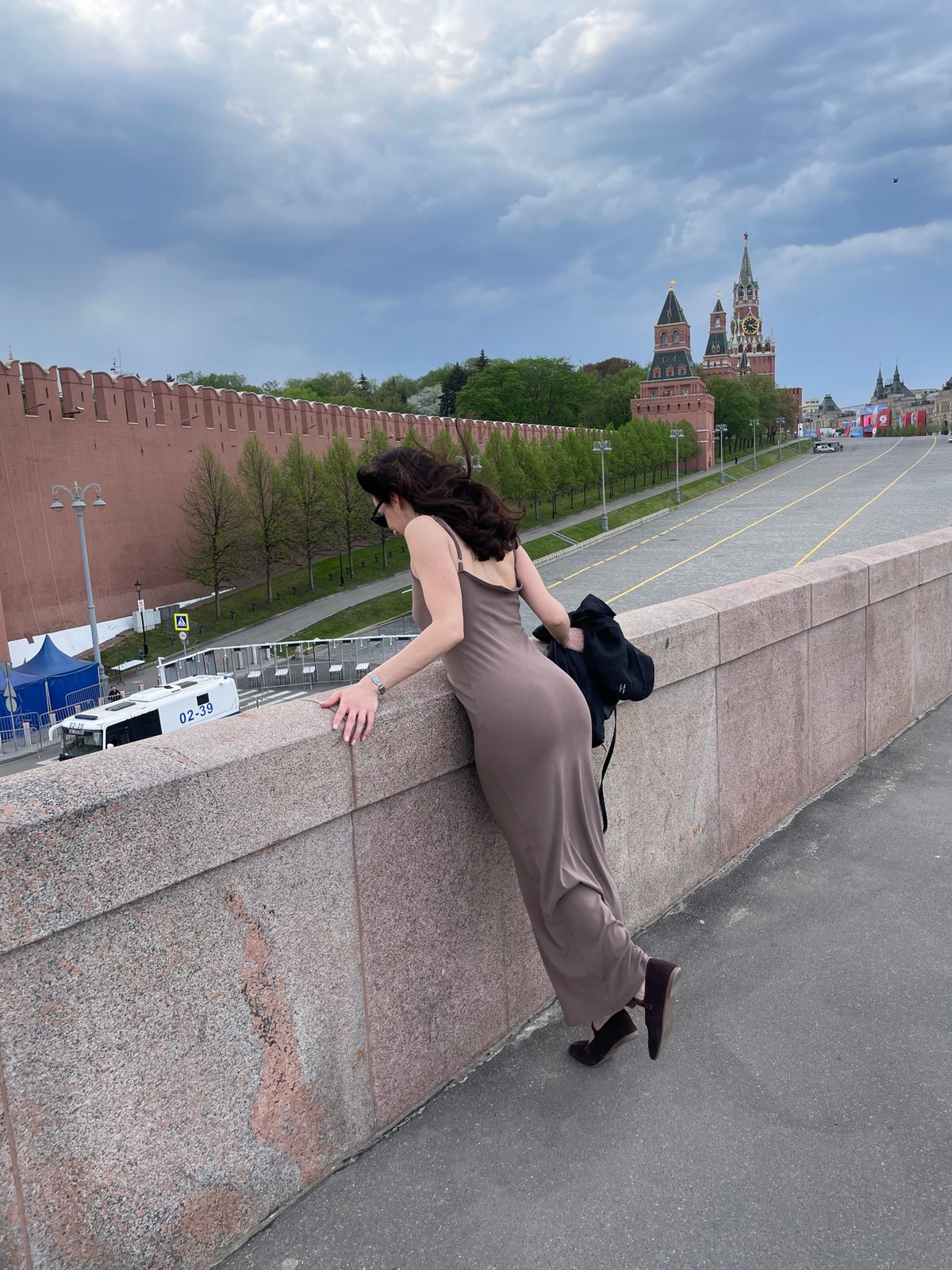 Woman leans over stone wall near Kremlin in Moscow
