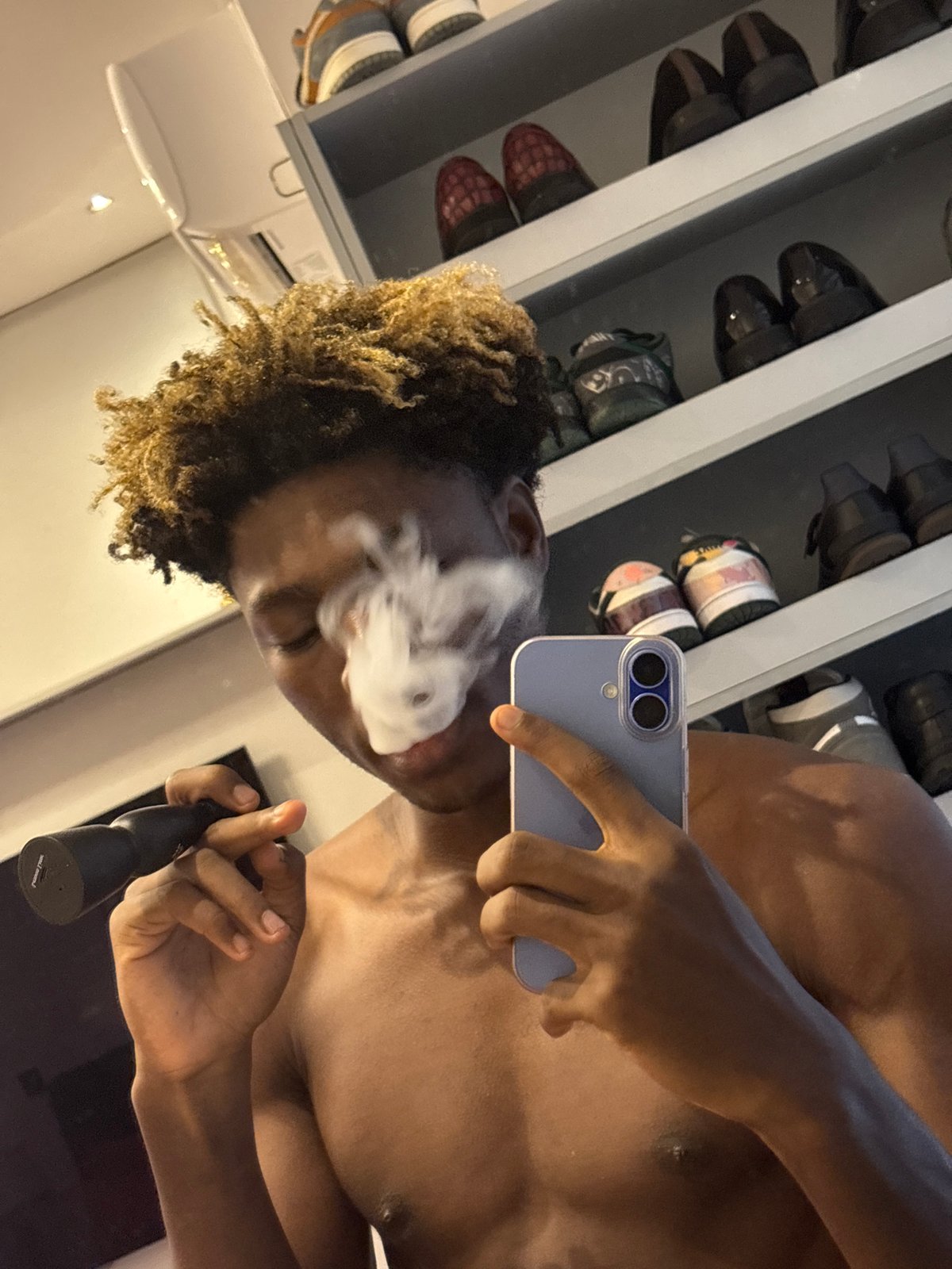 Person documents vaping session via smartphone selfies in Nigeria