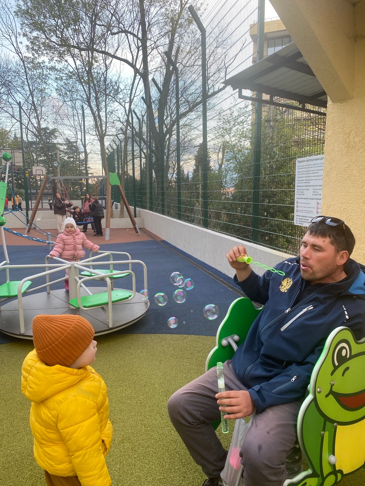 Man blows bubbles for child at Sochi playground