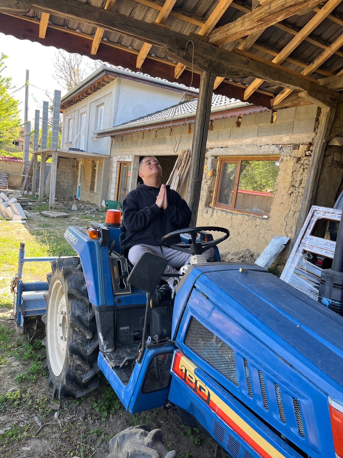 Person sits on blue tractor in rural Bulgaria