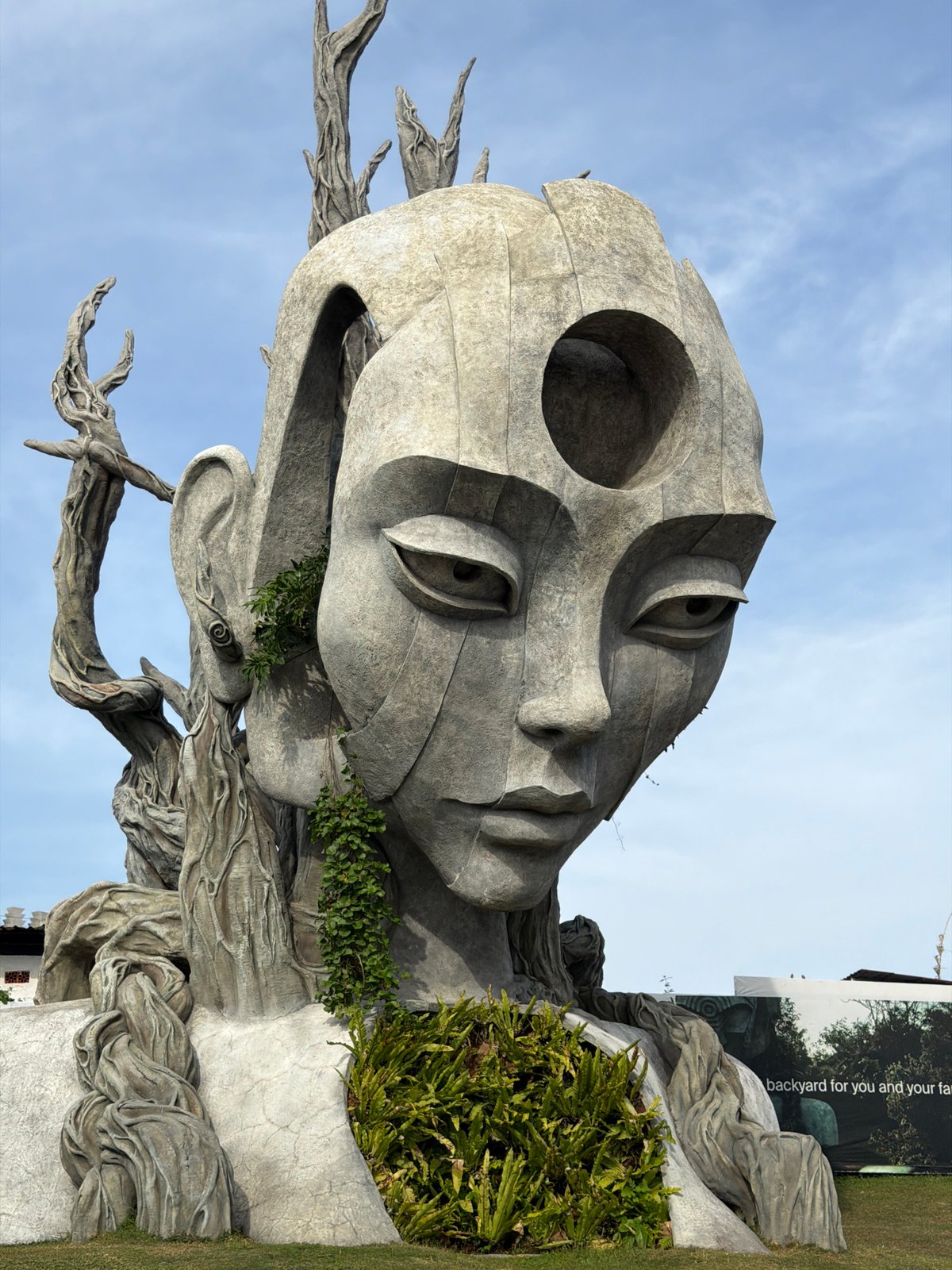 Monumental stone head sculptures merging with roots and greenery in Bali