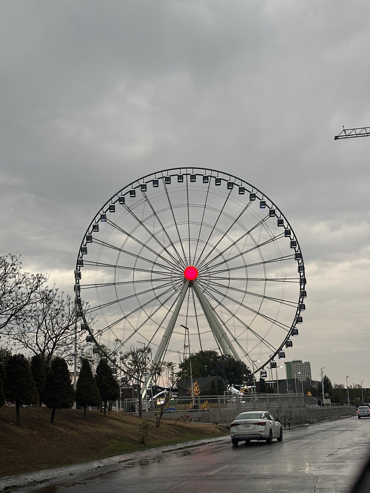 Rainy night drive past illuminated Ferris wheel in Puebla