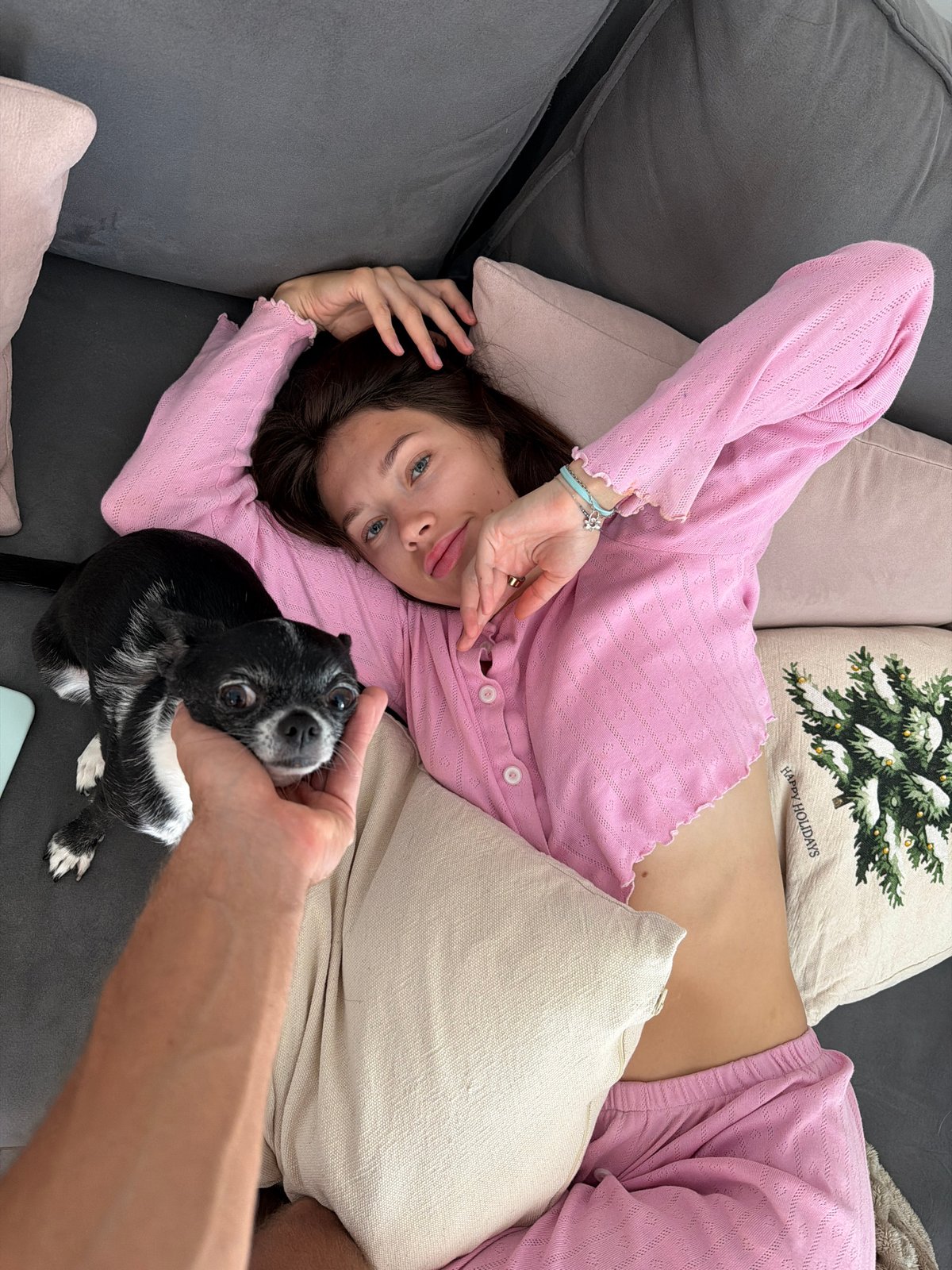 Woman relaxes with chihuahua on couch amid holiday decorations